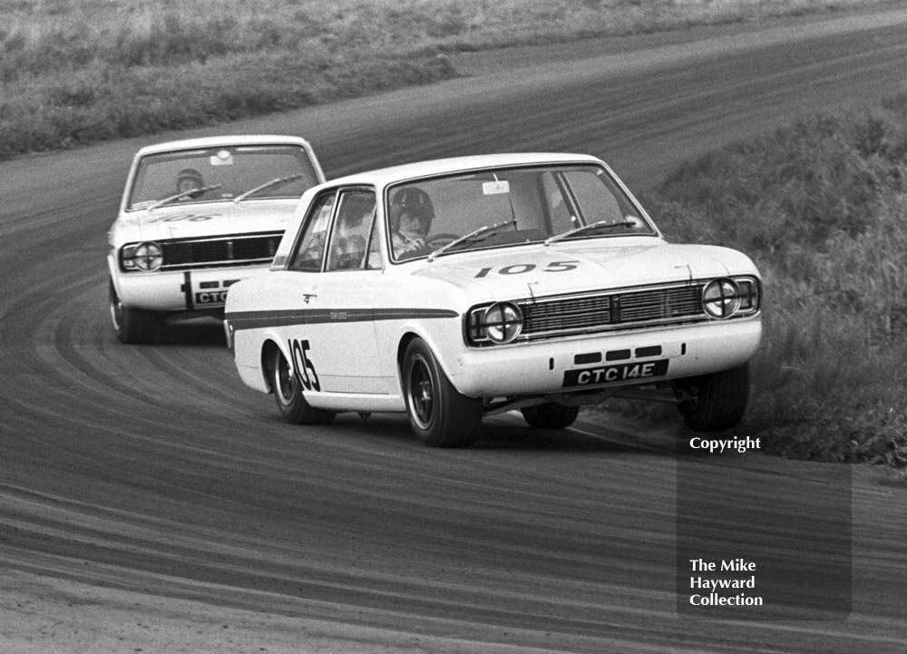 Team mates Graham Hill, CTC 14E, and Jacky Ickx, CTC 24E, driving Team Lotus Ford Cortinas at the Oulton Park Gold Cup meeting in 1967. Hill - who is on three wheels - and Ickx are pictured at Cascades Bend.
