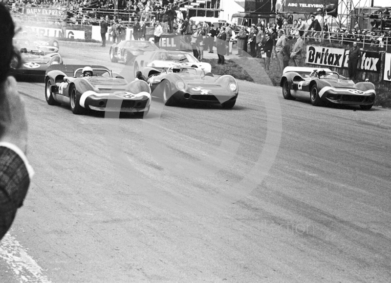 Leaving the grid are Bruce McLaren, McLaren Elva; David Hobbs, Team Surtees Lola; and Chris Amon, McLaren Elva; Silverstone International Trophy meeting 1966.
