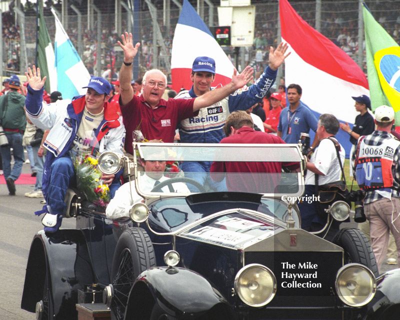 Murray Walker sets off on a lap of honour with Damon Hill and Jacques Villeneuve, Silverstone, British Grand Prix 1996.
