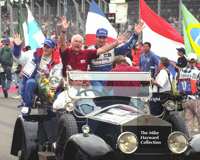 Murray Walker sets off on a lap of honour with Damon Hill and Jacques Villeneuve, Silverstone, British Grand Prix 1996.
