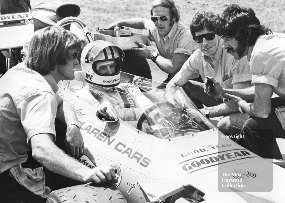 Denny Hulme, McLaren M19A, Cosworth V8, with mechanics and team manager Alastair Caldwell (left), 1971 British Grand Prix, Silverstone.
