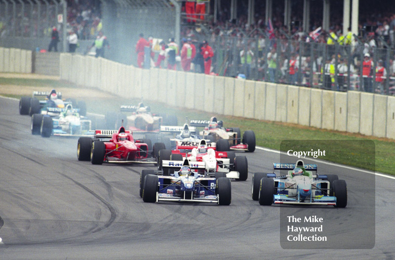 First lap into Copse Corner with Jacques Villeneuve, Williams Renault FW18 on the inside line, Silverstone, British Grand Prix 1996.
