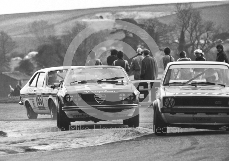 Jon Dooley, Napolina Alfa Romeo Alfa Alfetta GT, bounces over the curb, followed by Bernard Unett, Chrysler Avenger GT, Tricentrol British Touring Car Championship, F2 International meeting, Thruxton, 1977. Ahead of them is Richard Lloyd, VW Golf.
