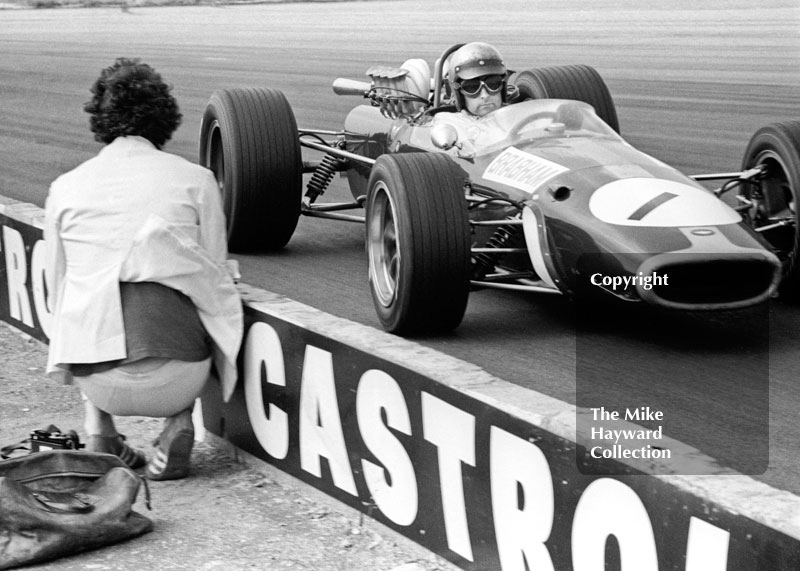 A photographer gets up close to Jack Brabham, Repco Brabham V8 BT24/1, at Copse Corner, Silverstone, 1967 British Grand Prix.
