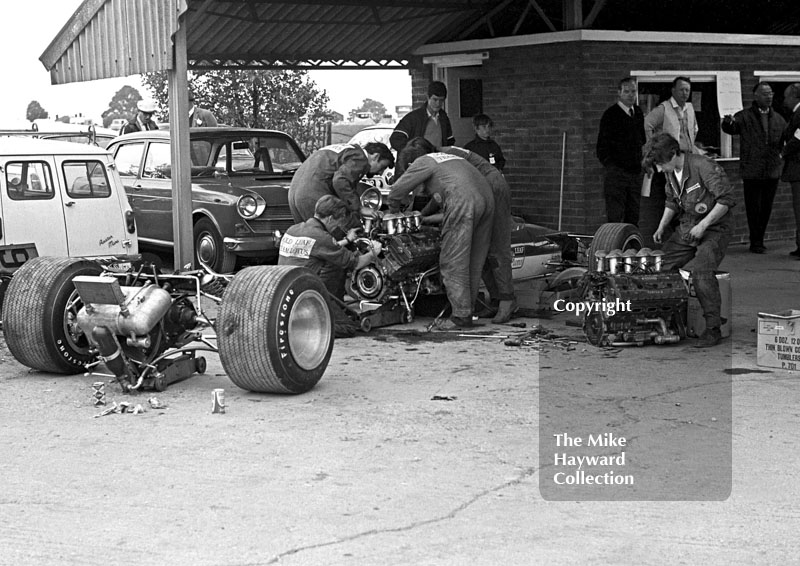 Gold Leaf Team Lotus mechanics change the engine of Graham Hill's Lotus 49B in the paddock, Silverstone, 1969 British Grand Prix.
