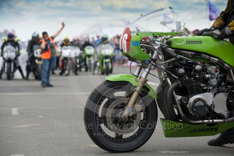 Classic bikes wait to move off in the paddock, Silverstone Classic, 2010