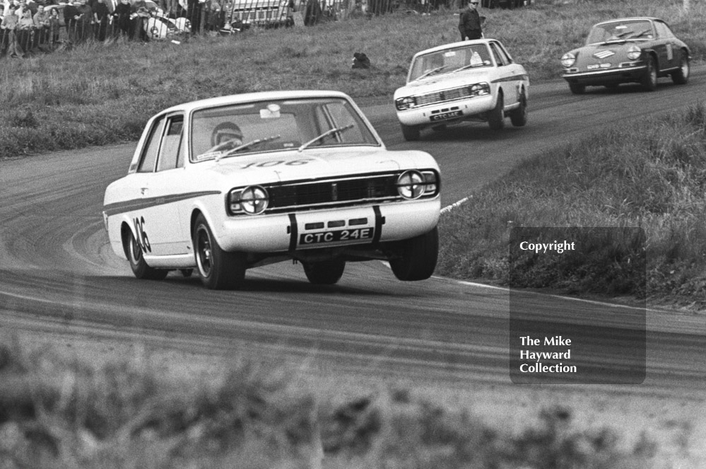 Jacky Ickx, Team Lotus Cortina, CTC 24E, on three wheels, leads team mate Graham Hill, CTC 14E, on two wheels, Oulton Park Gold Cup meeting, 1967.
