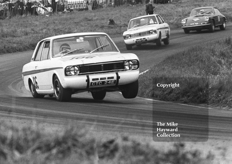 Jacky Ickx, Team Lotus Cortina, CTC 24E, on three wheels, leads team mate Graham Hill, CTC 14E, on two wheels, Oulton Park Gold Cup meeting, 1967.
