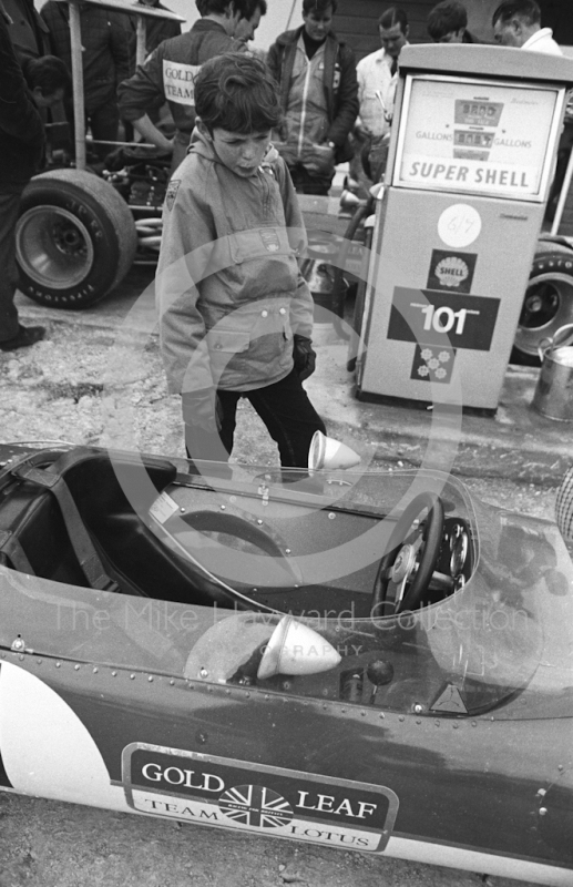 A young admirer studies the cockpit of Graham Hill's Gold Leaf Team Lotus 49B as mechanics fill up the cars at the paddock pumps, Silverstone, International Trophy 1969.
