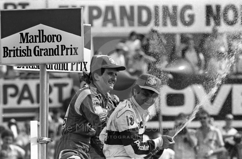 Winner Alain Prost, Renault RE40, and second placed Nelson Piquet, Brabham BT52B, spray champagne on the podium, British Grand Prix, Silverstone, 1983
