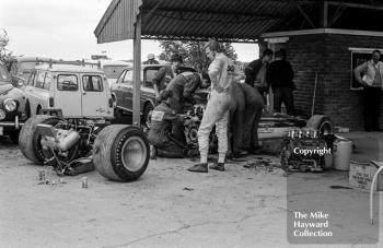 Ronnie Peterson watches over Gold Leaf Team Lotus mechanics change the engine of Graham Hill's Lotus 49B in the paddock, Silverstone, 1969 British Grand Prix. Ronnie was taking part in the Formula 3 race.
