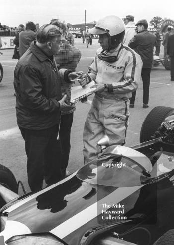 Richie Ginther, Cooper Maserati V12 T81, chats to a mechanic on the grid before the start of the Silverstone International Trophy, 1966.
