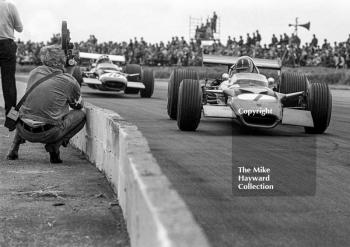 A film cameraman gets up close as Graham Hill, Gold Leaf Team Lotus Cosworth 49B, leads Jo Siffert, Rob Walker Lotus 49B, at Copse Corner, Silverstone, 1969 British Grand Prix.
