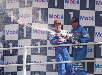 Jacques Villeneuve and Gerhard Berger spray champagne on the podium, Silverstone, British Grand Prix 1996.
