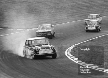 Steve Neal, Cooper Car Company Mini Cooper S, leads through South Bank Bend, followed by Roger Taylor, Ford Escort (XTW 378F), John Rhodes, Mini, and Tony Lanfranchi, Hillman Imp, Brands Hatch, Grand Prix meeting 1968.
