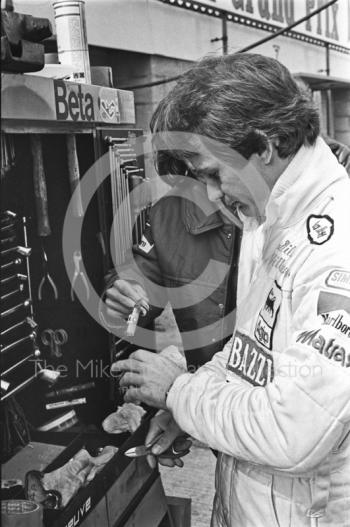 Gilles Villeneuve uses a pair of mechanic's pliers to trim his fingernails in the pits at Silverstone, British Grand Prix 1979.
