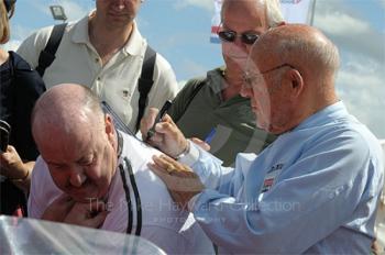 Sir Stirling Moss signs an autograph in the paddock ahead of the RAC Woodcote Trophy, Silverstone Classic 2009.